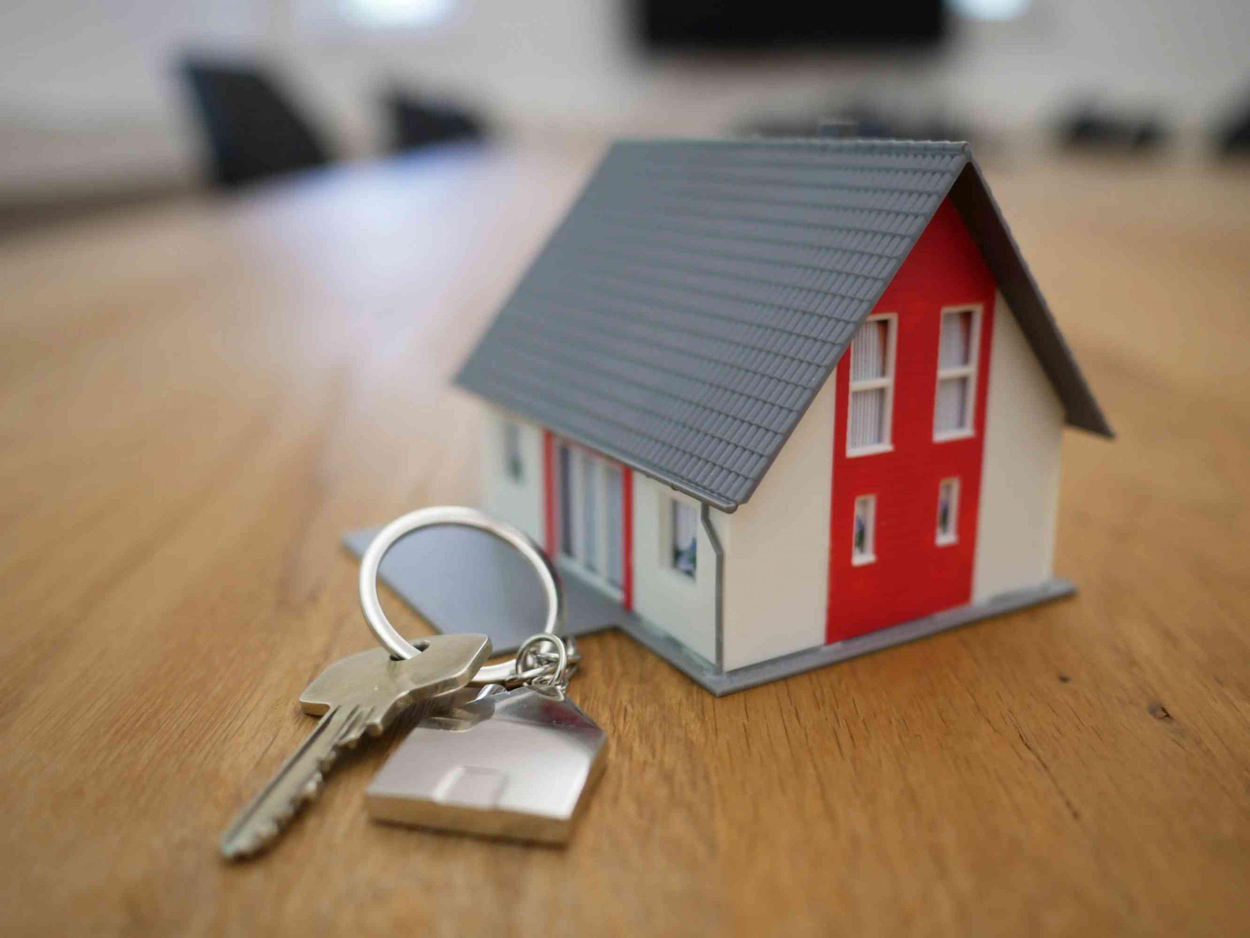 Miniature house with a key to represent things to know before buying a house