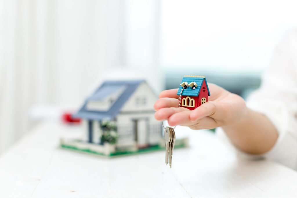 Agente inmobiliario sosteniendo una casa miniatura para demostrar 5 trucos para vender una casa rápido en 2023