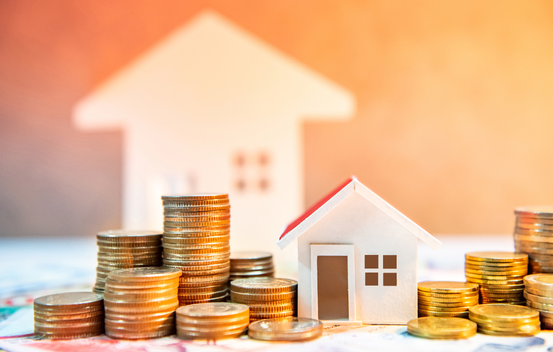 Casa en miniatura con monedas apiladas para ejemplificar el artículo del blog que habla de las mejores inversiones inmobiliarias
