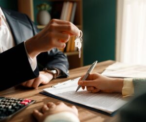 imagen de una persona firmando un documento mientras le entregan unas llaves para representar que se puede comprar casa sin crédito en Estados Unidos